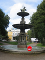 A red puffle standing on the edge of a fountain.