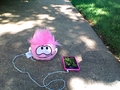 A pink puffle listening to an iPhone.