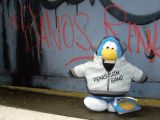 A rockstar penguin standing near graffiti.