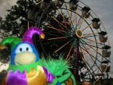 A jester and a green puffle near a ferris wheel.