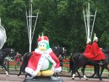 A king penguin, with men riding horses in the background.